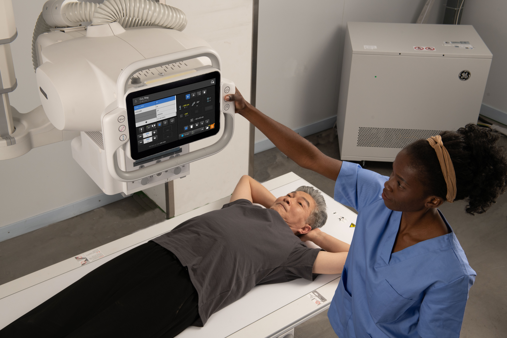 An X-ray tech using a GE Healthcare Definium Tempo fixed X-ray system with a patient on the table.