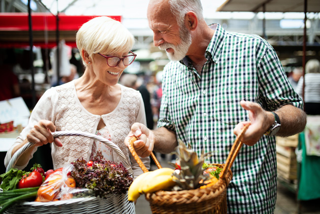 Starejši par nakupuje živila na tržnici - Simbolna fotografija za pravo prehrano za zdravo srce