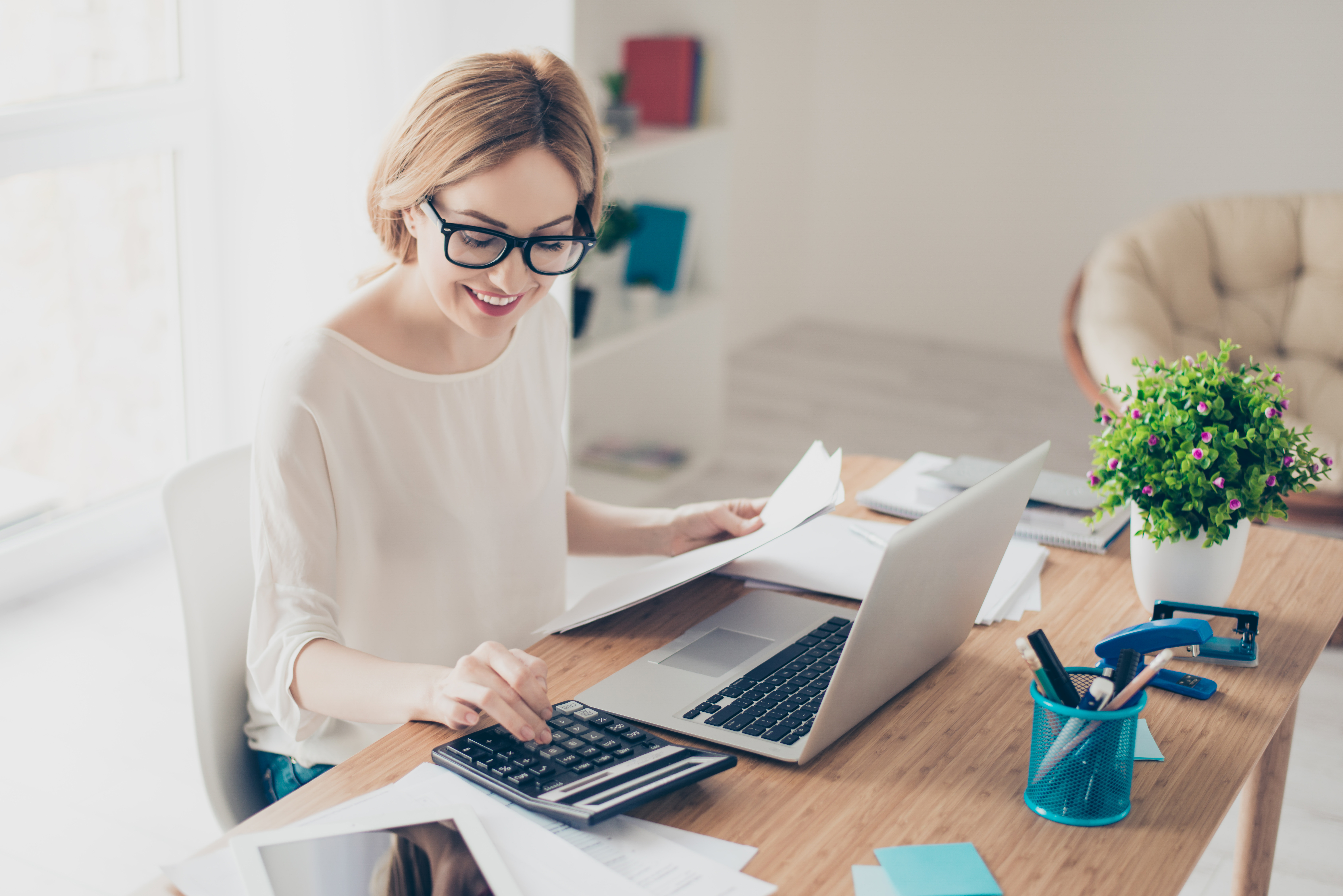 Happy cute  pretty accountant working with computer and calculator