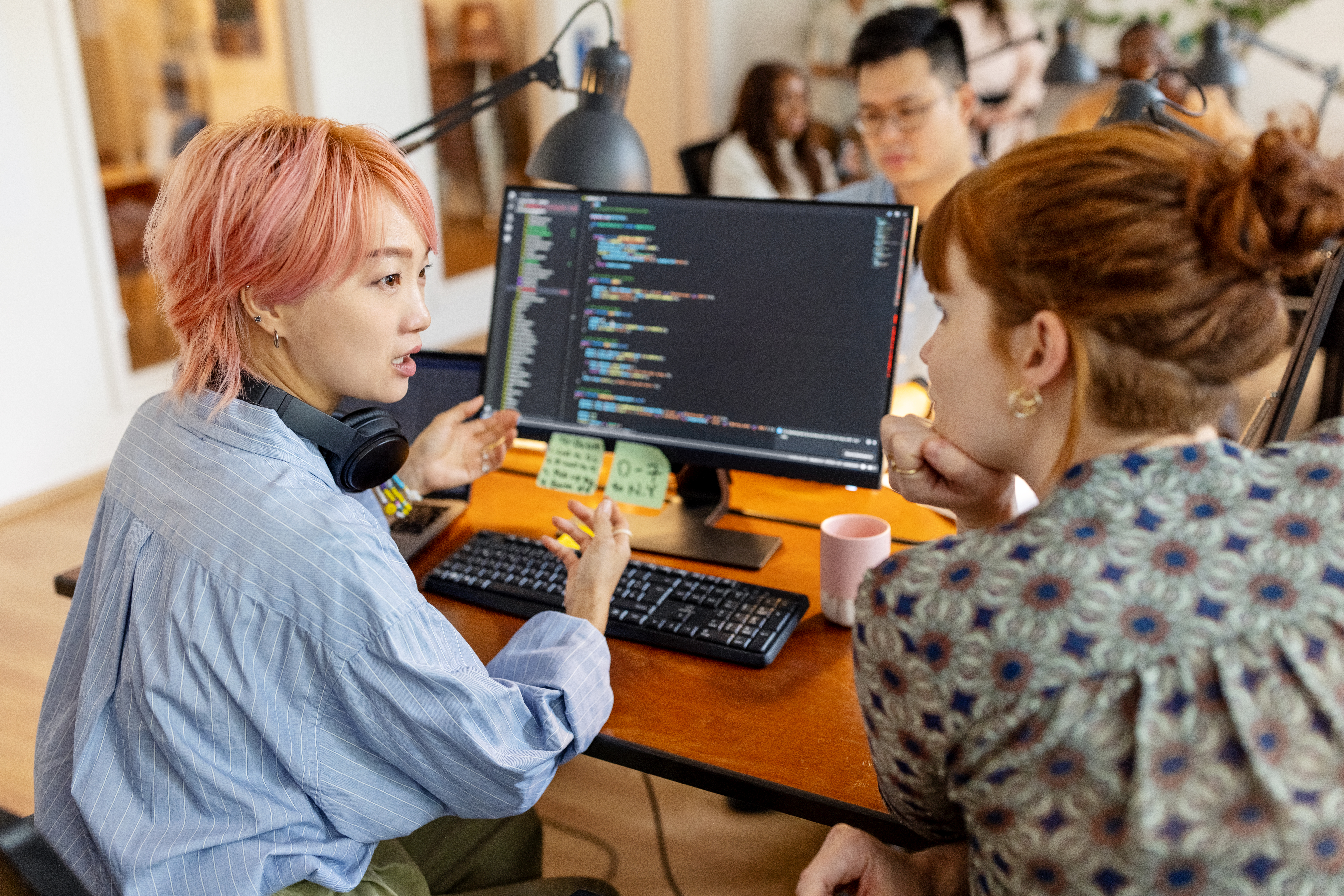 Two workers at a computer discussing enterprise mobility management solutions.