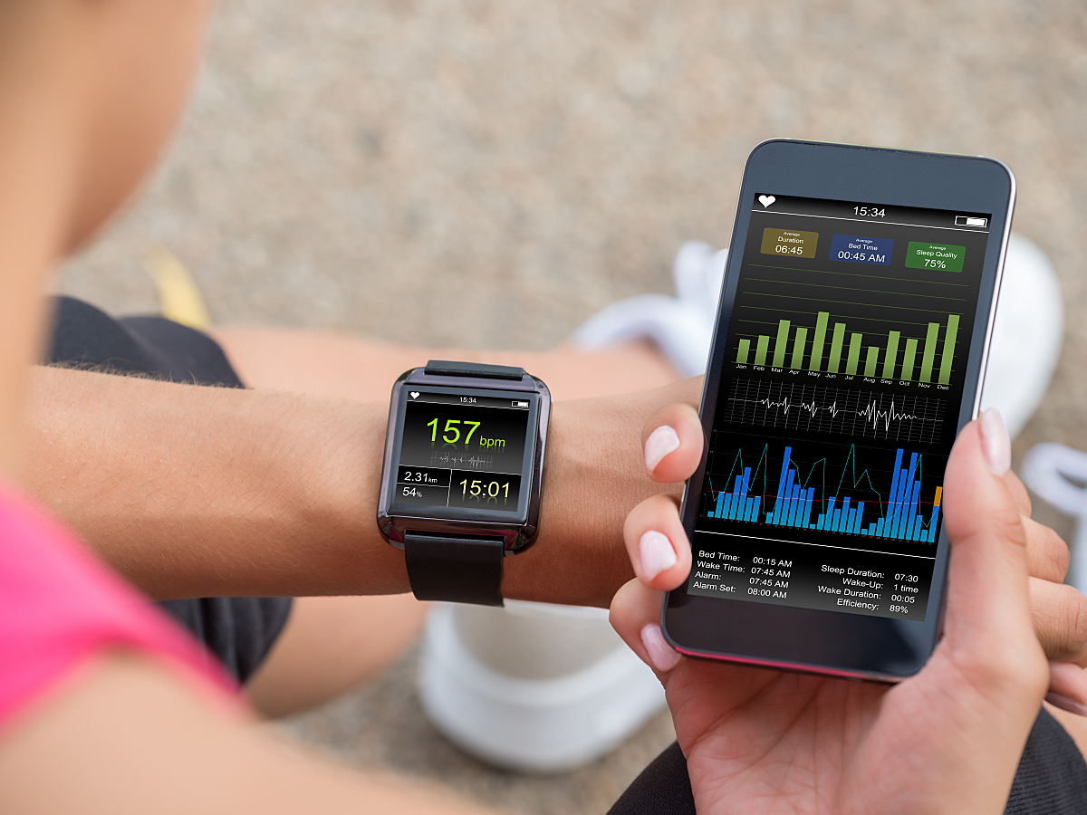 A female runner checks her smartwatch and mobile phone to measure her heart rate recovery. 
