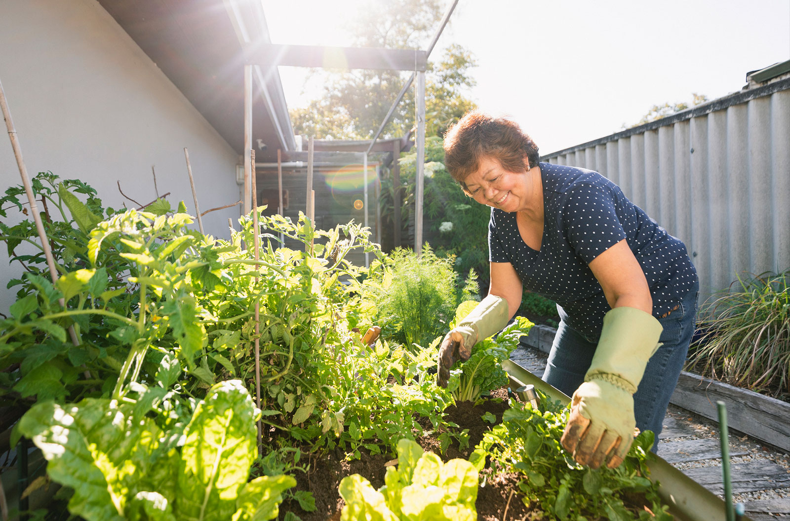 A woman smiling as she works in a garden. 