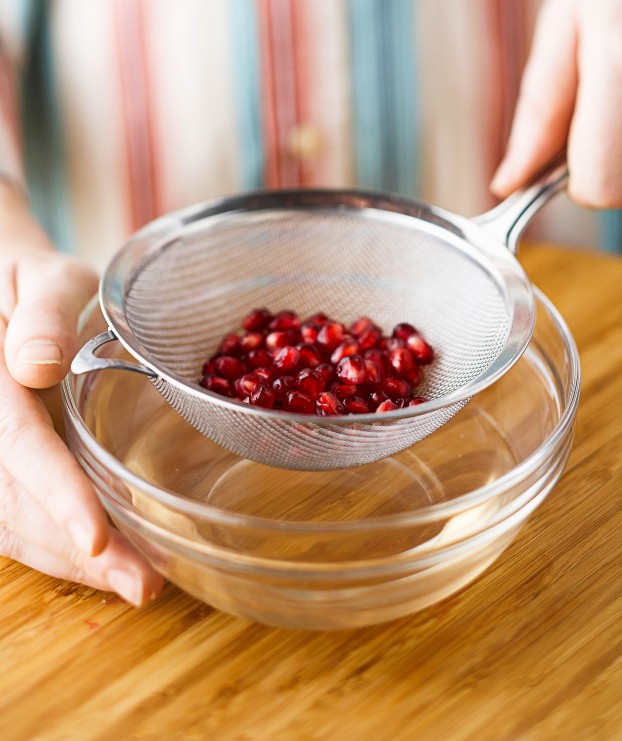 draining pomegranate seeds with a sieve