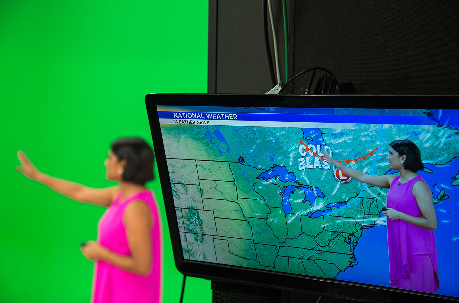 A meteorologist in front of a green screen.