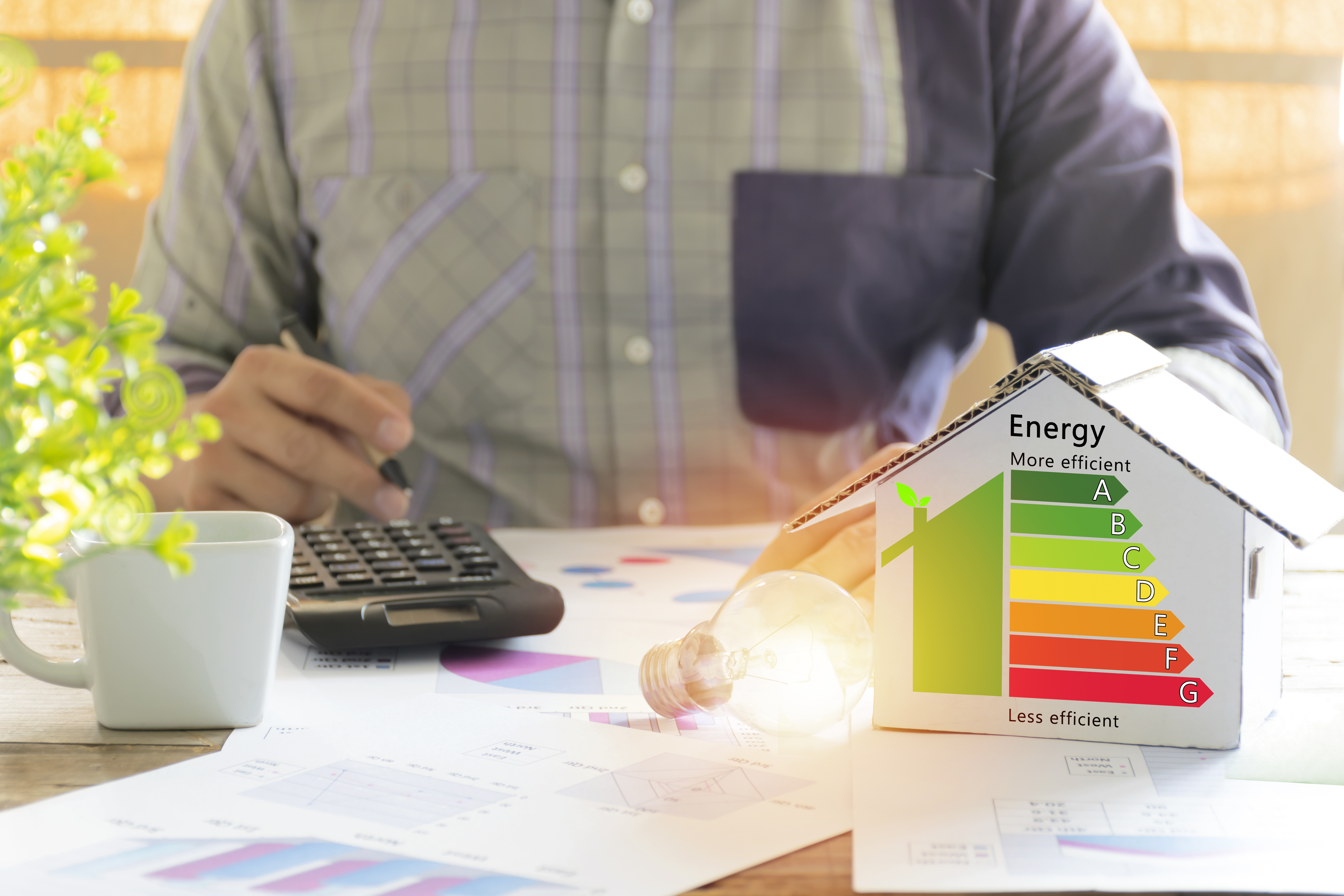 Men who are calculating cost savings from energy. Hand holding a pen.