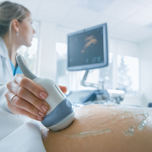 In the Hospital, Close-up Shot of the Doctor does Ultrasound / Sonogram Procedure to a Pregnant Woman. Obstetrician Moving Transducer on the Belly of the Future Mother.