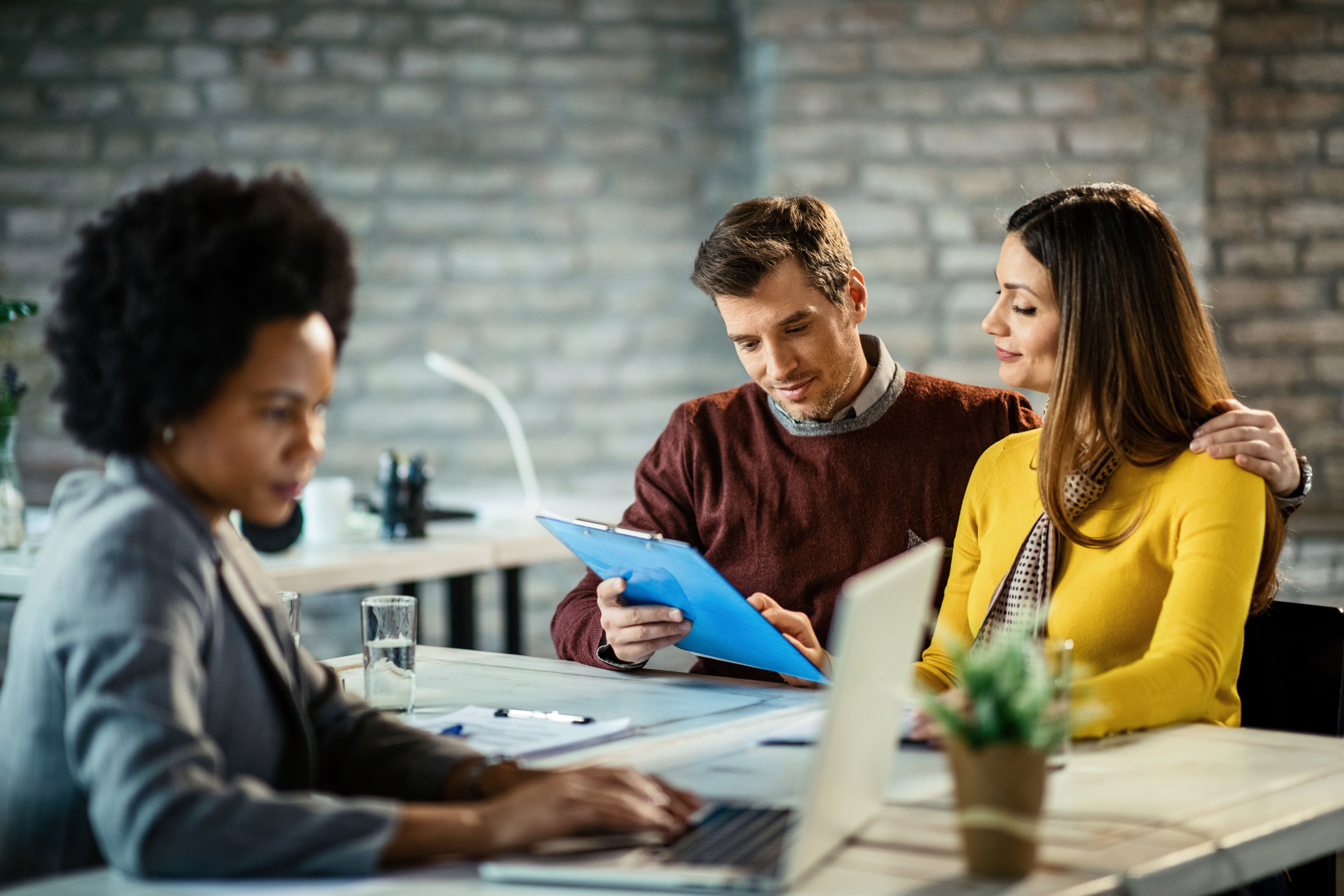 Smiling couple analyzing their financial reports on a meeting with insurance agent.