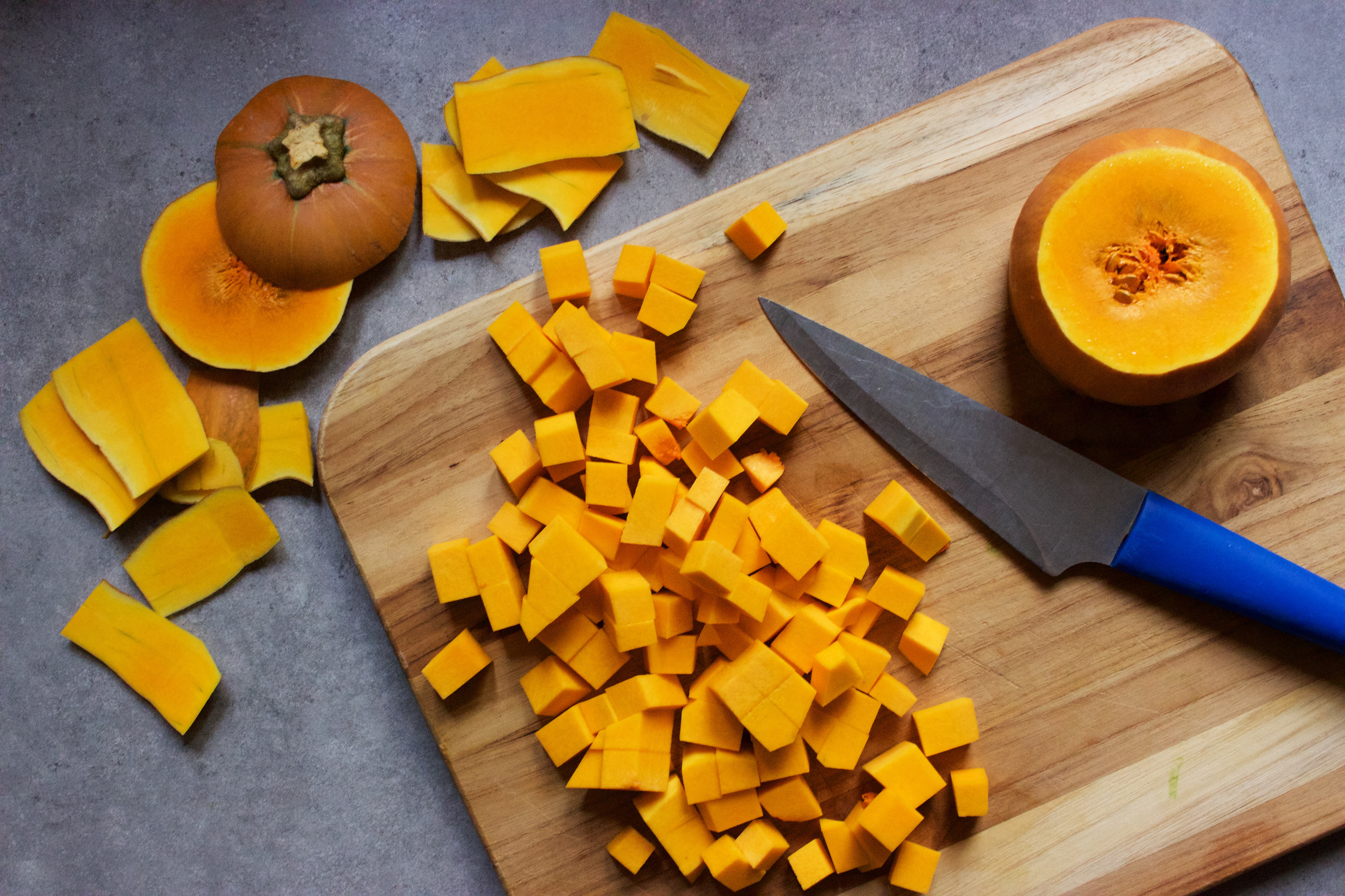 Chopping butternut squash into cubes on a wooden cutting board