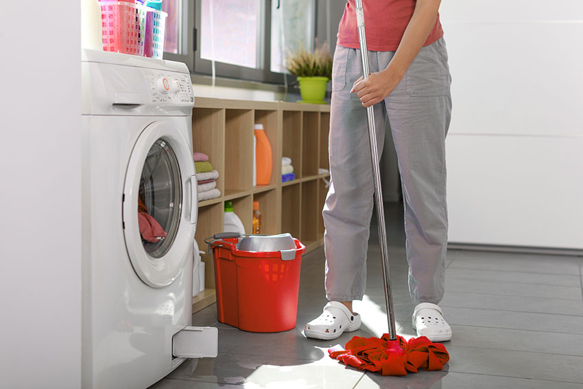 Ženska čisti tla, ker ji pralni stroj pušča vodo