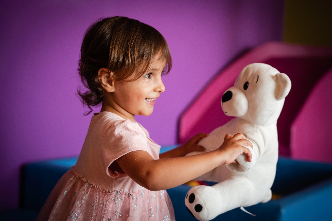 Menina segurando bicho de pelúciaDescrição gerada automaticamente