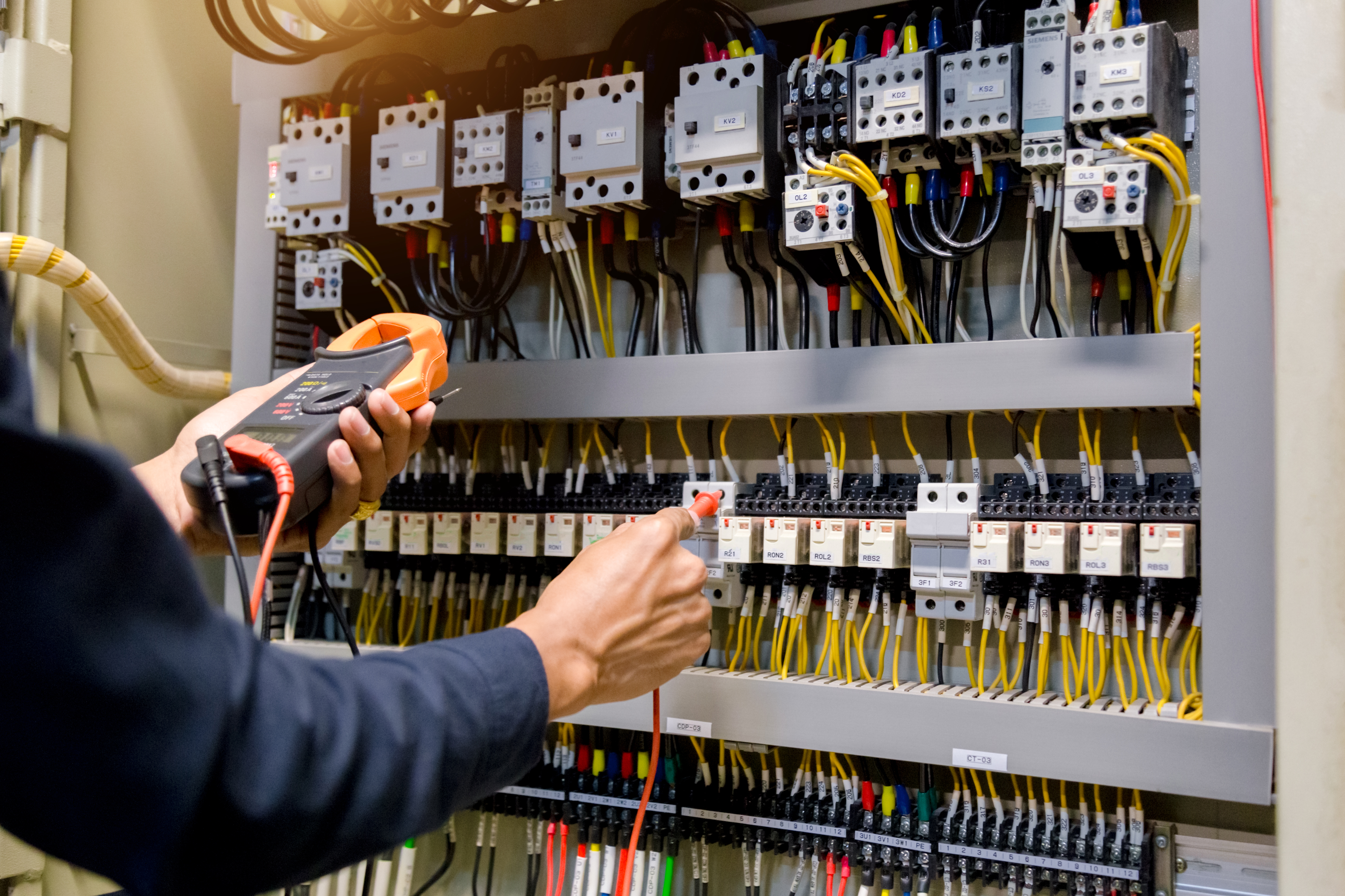 Electrician engineer work  tester measuring  voltage and current of power electric line in electical cabinet control.