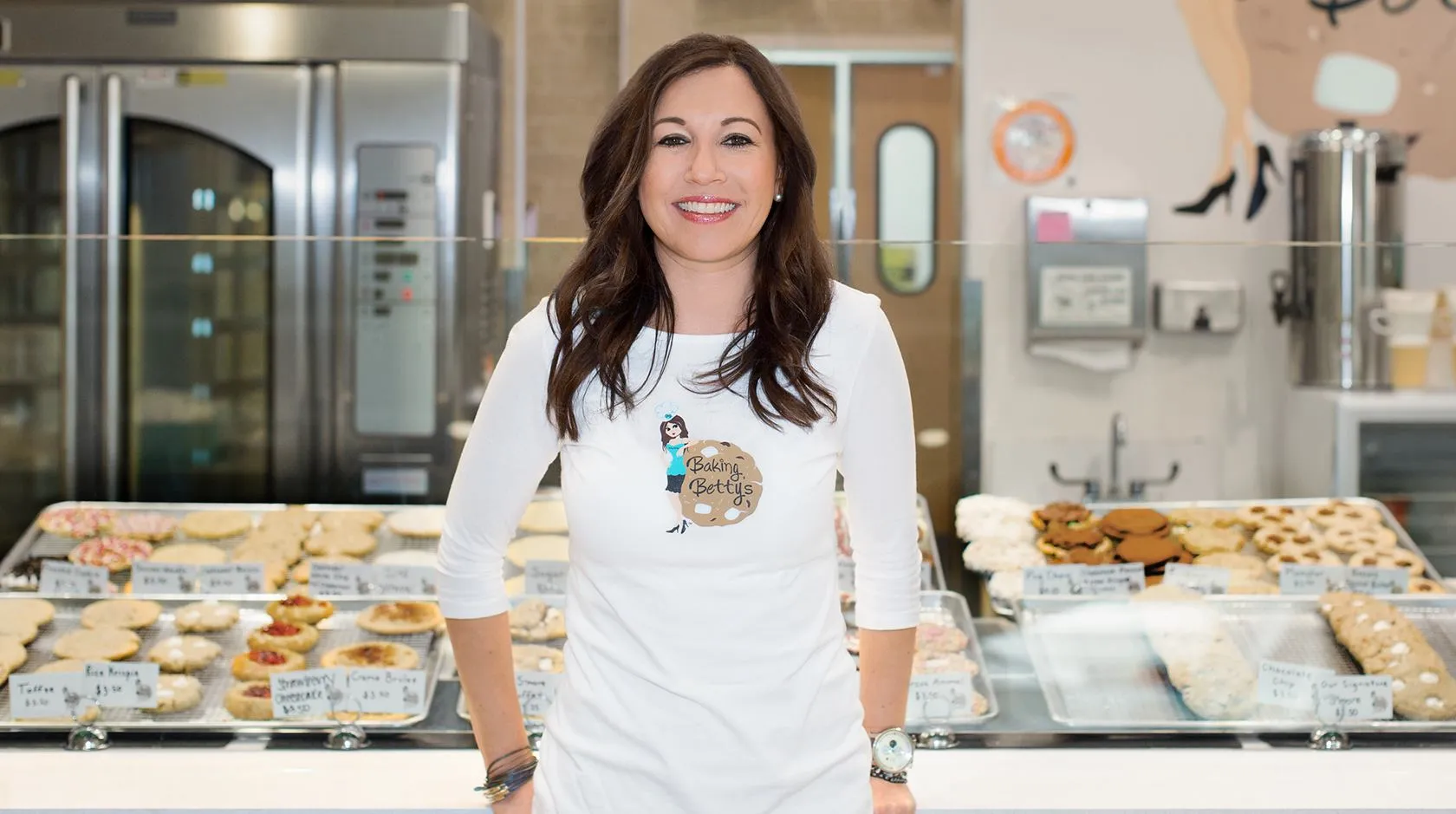 Woman standing in front of a case of pastries in a bakery