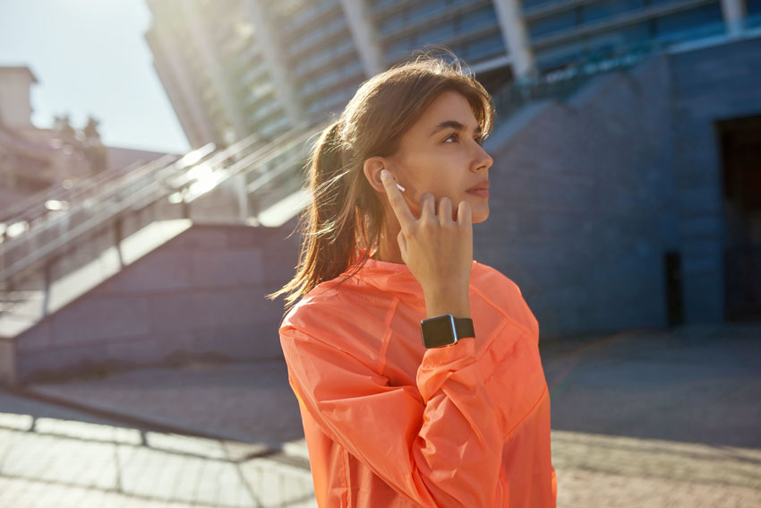Najboljša tekaška oprema - dekle na sliki se pripravlja na tek z dodatnimi pripomočki poleg športne ure