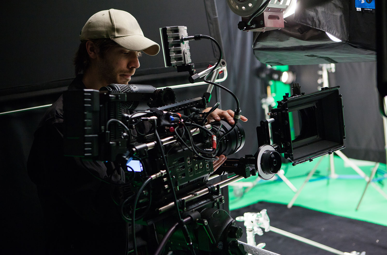 A camera operator setting up for a shoot with a camera and a green screen. 