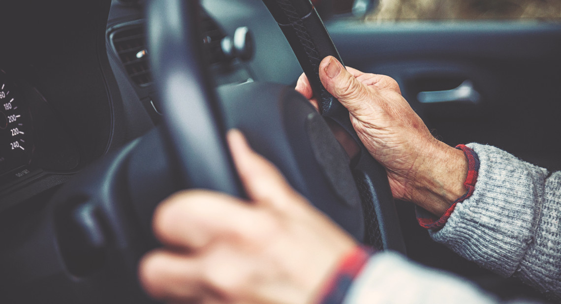 The hand of an elderly gentleman on the steering wheel