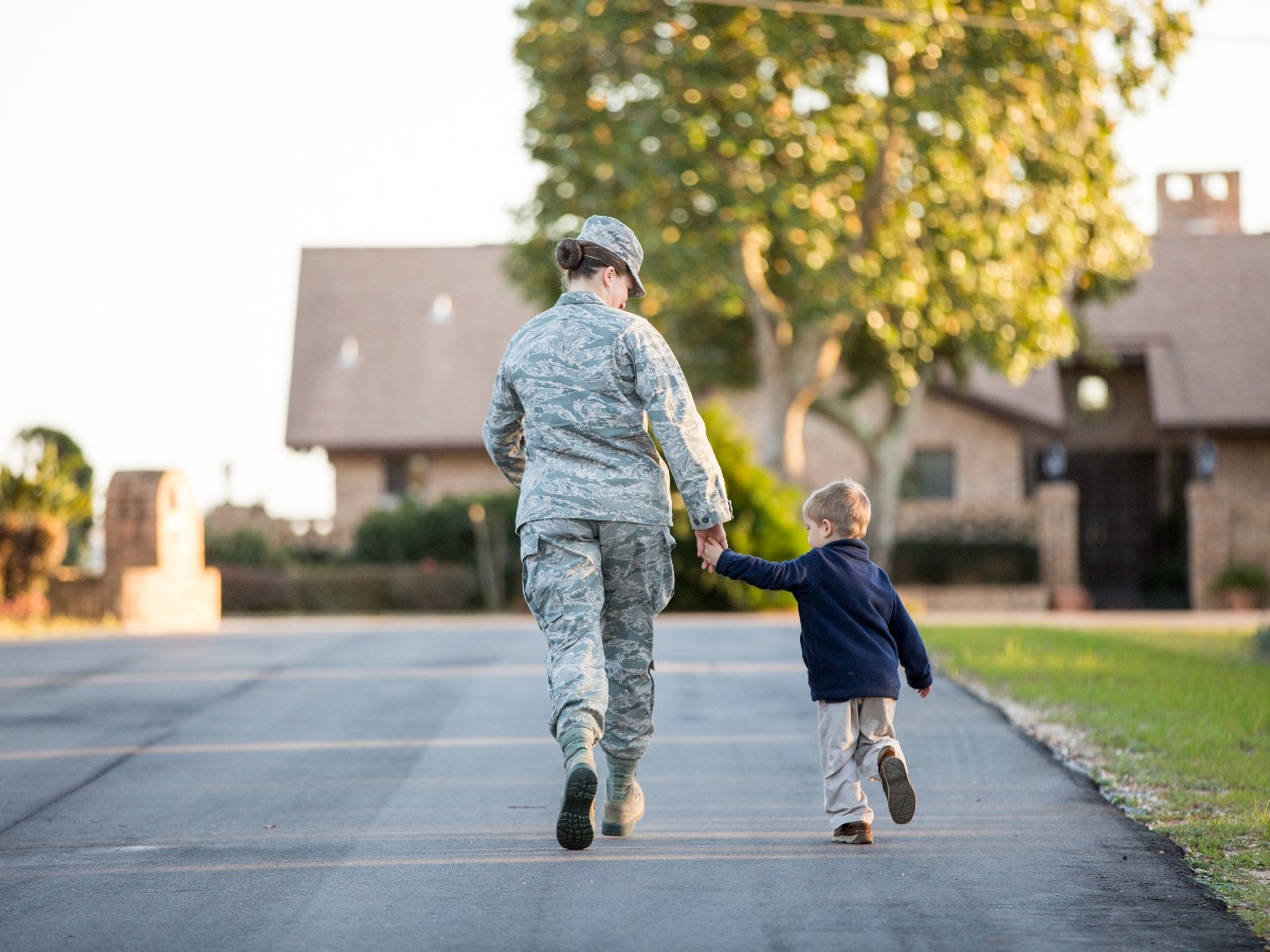 Female soldier holding hands walking with son