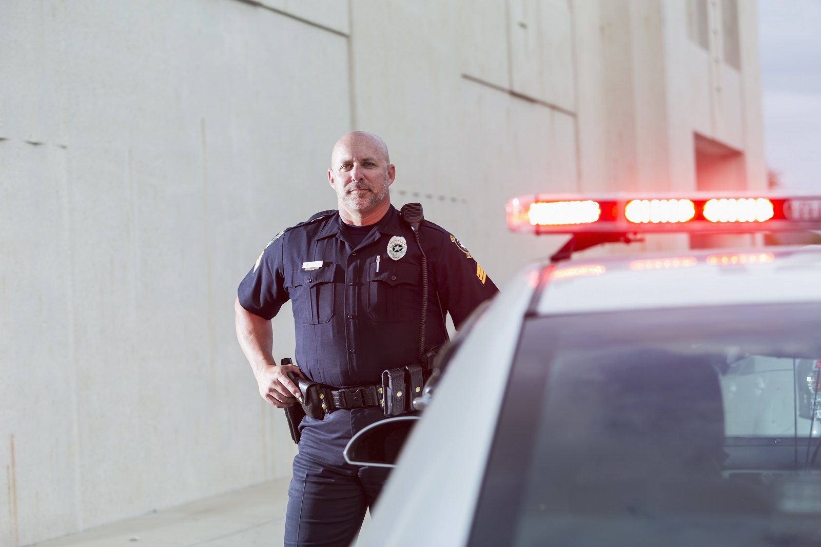 A police officer stands next to a cruiser car equipped with modern police technology.