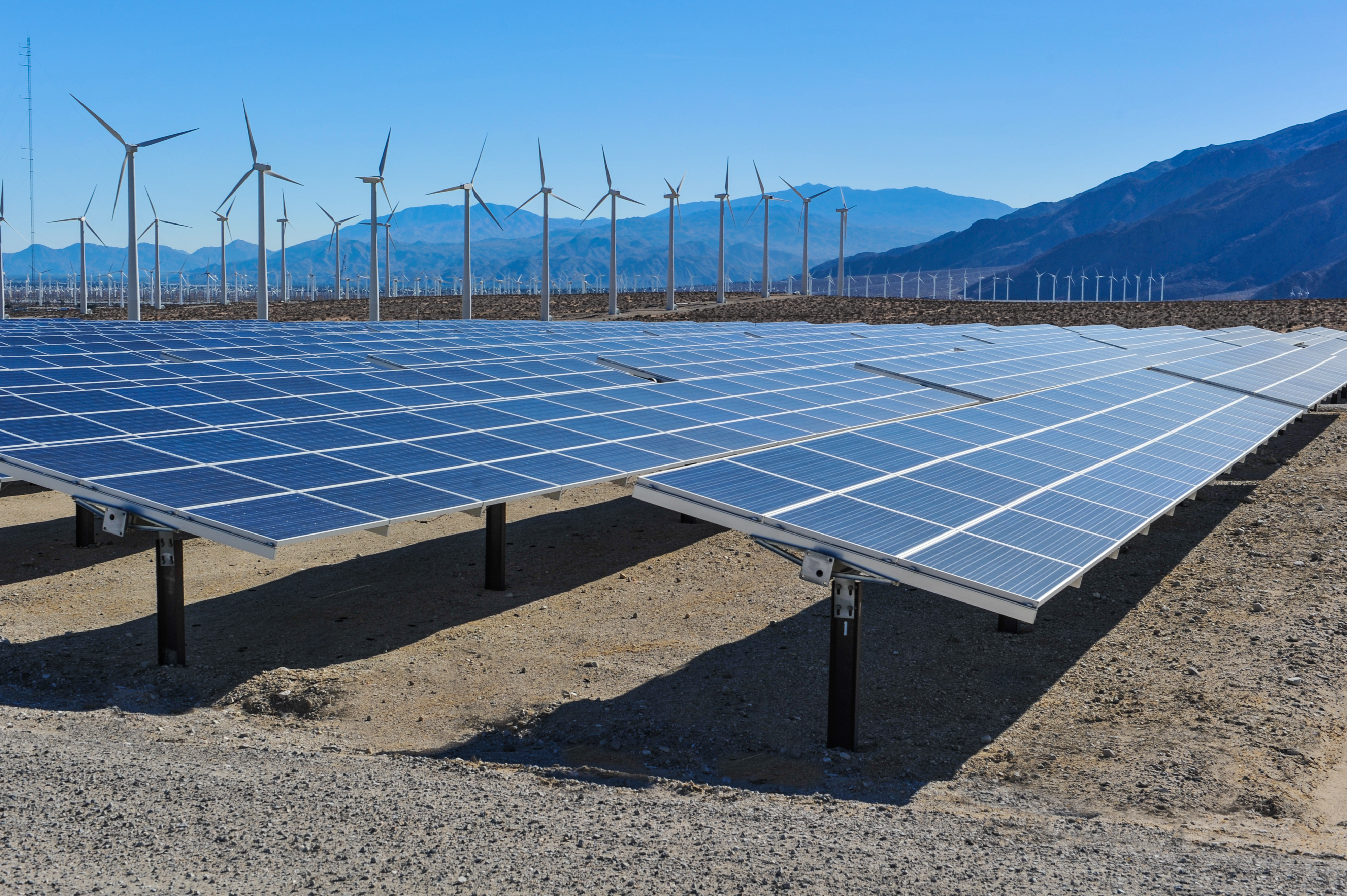 Solar panels in front of wind turbines and mountians