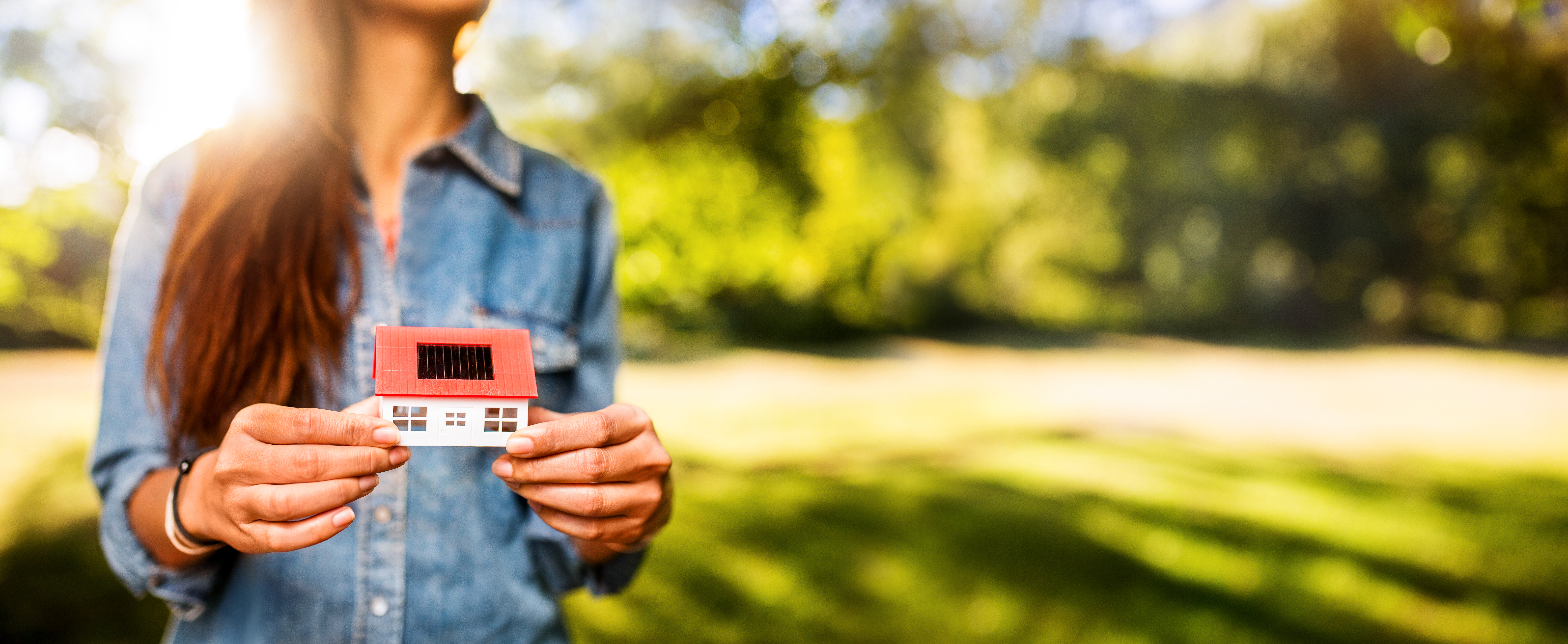 Woman holding model of new home on a sunny lawn