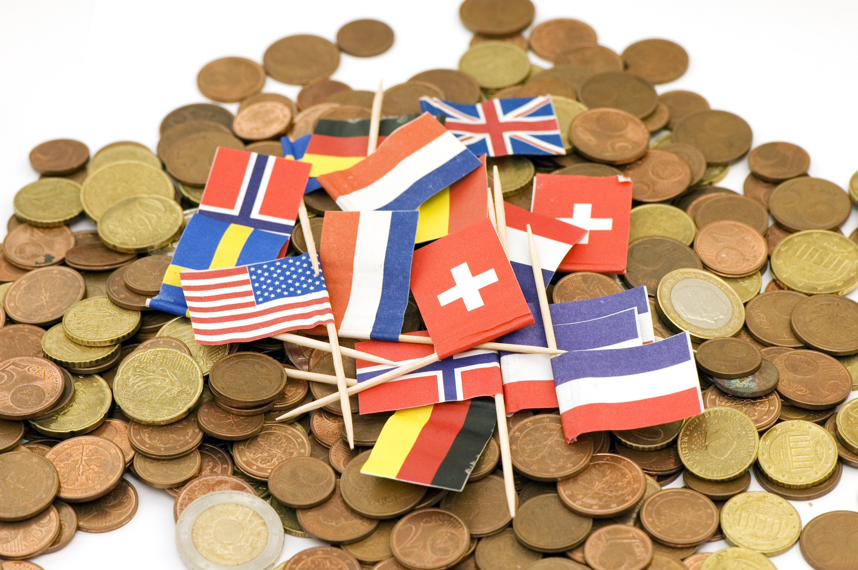 Close-up of international flags sitting on euro coins background.
