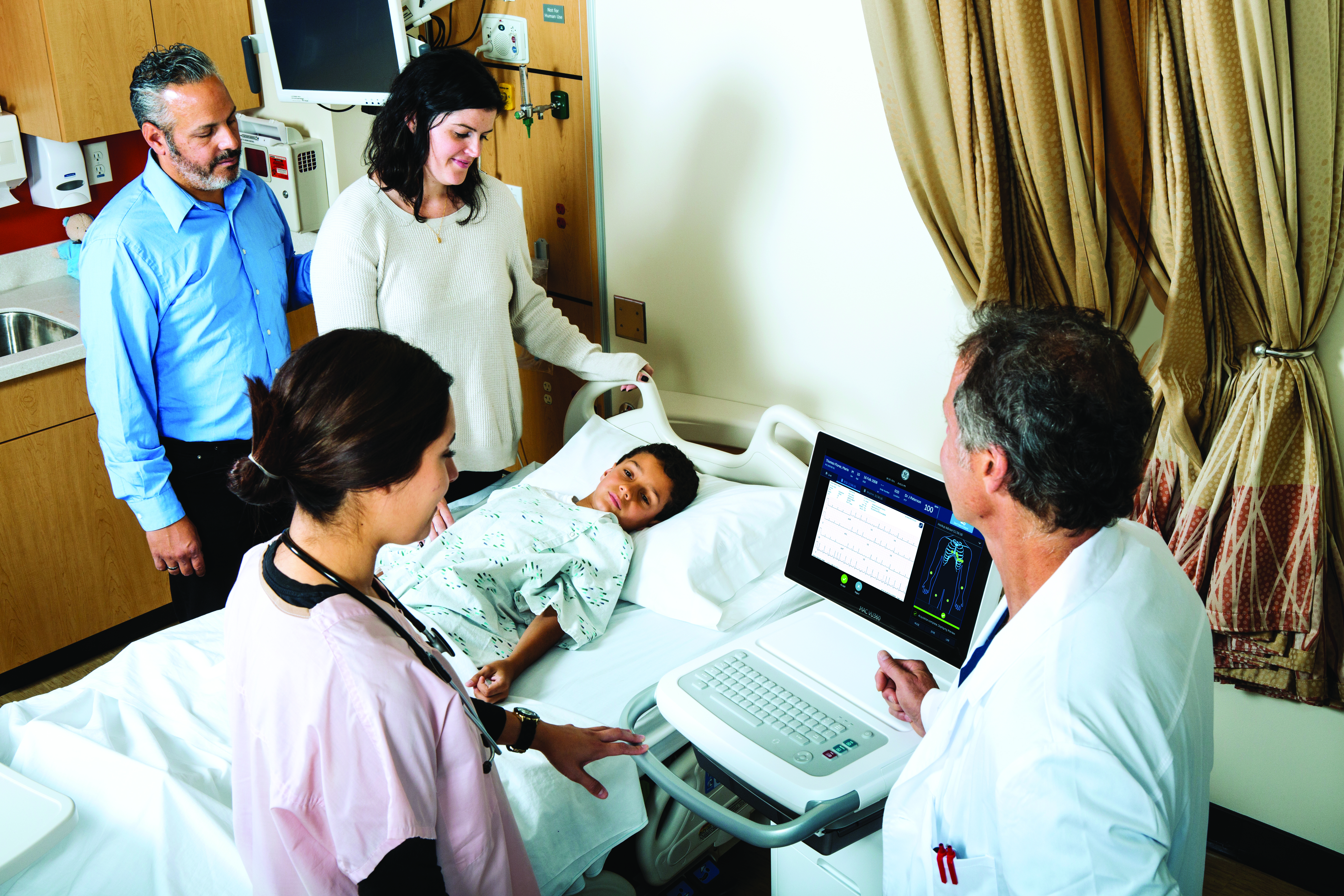 Doctor, nurse and parents around the bedside of a child receiving and ECG exam.