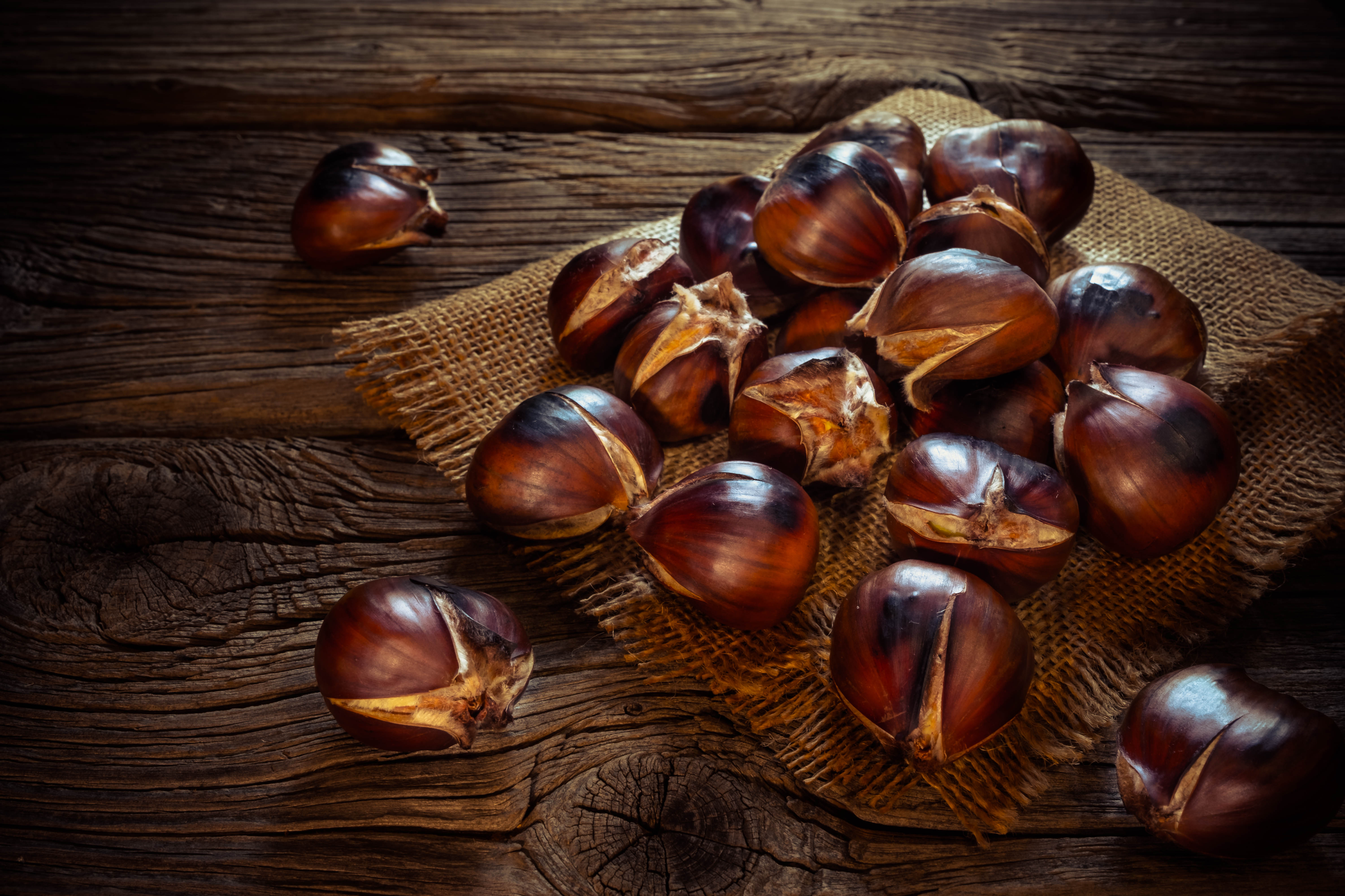 Roasted chestnuts on a sack napkin and wooden background
