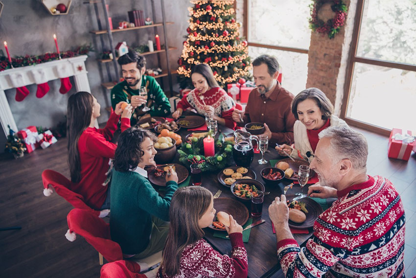 Razširjena družina v okrašeni sobi uživa v zdravi božični večerji
