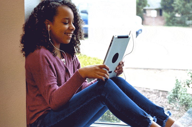 Middle schoolgirl uses digital tablet with earbuds