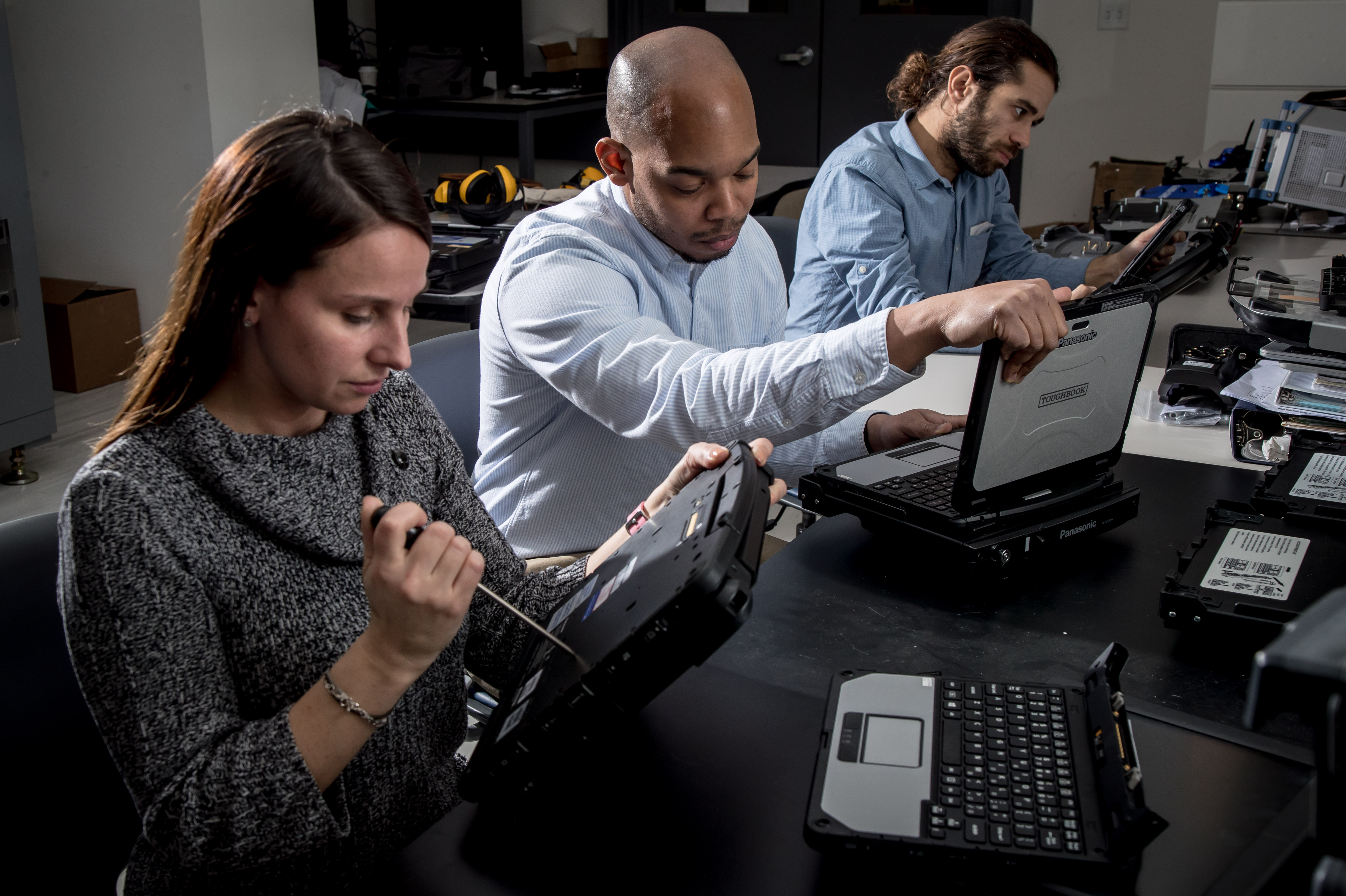 Three workers with rugged devices for use in enterprise mobility management.