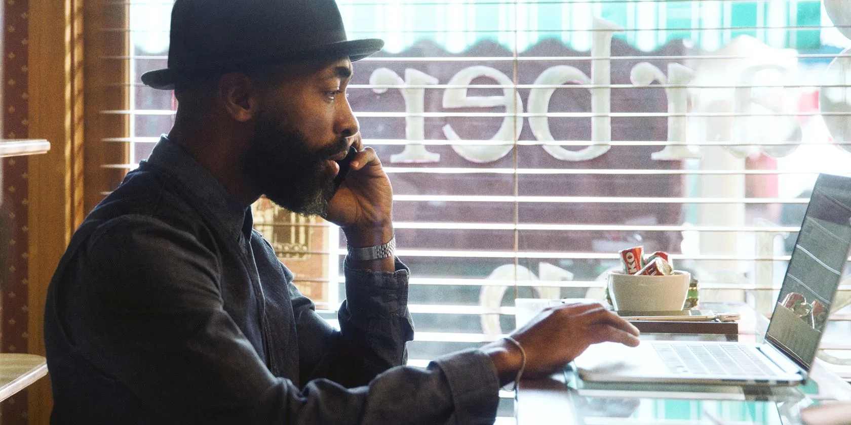 Photo of man talking on the phone and using a laptop