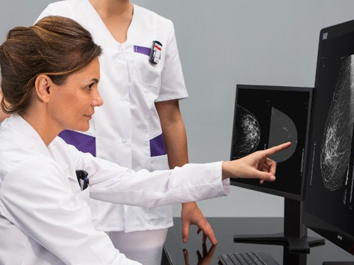Physician and imaging tech review mammography images on a computer