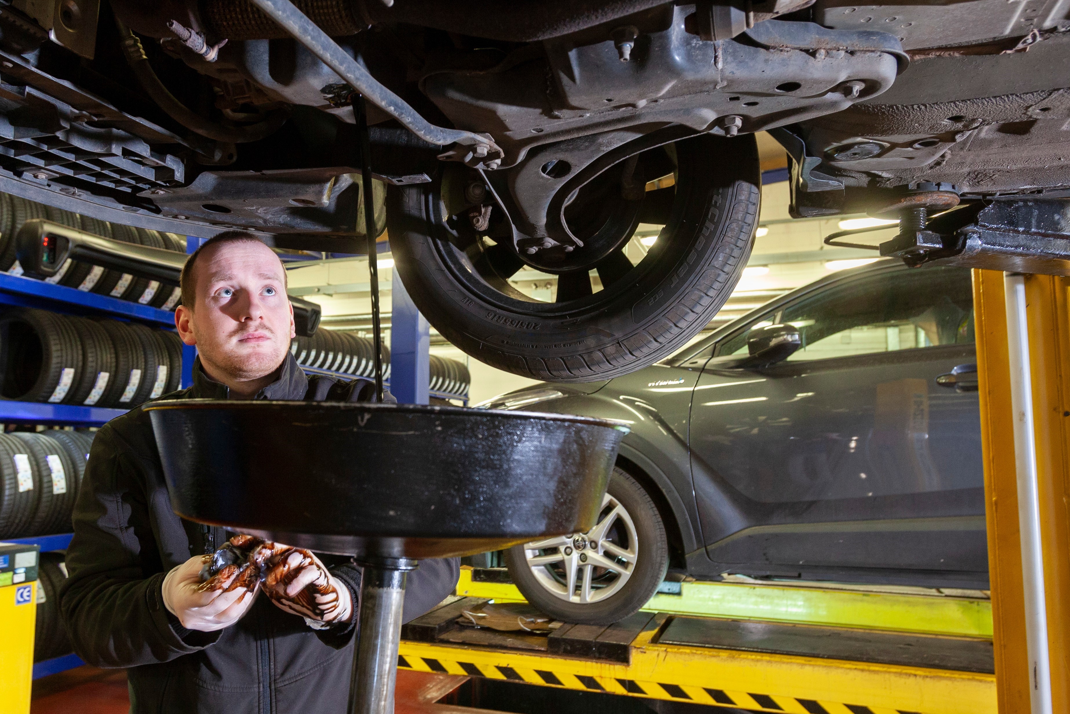 car mechanic draining oil in garage