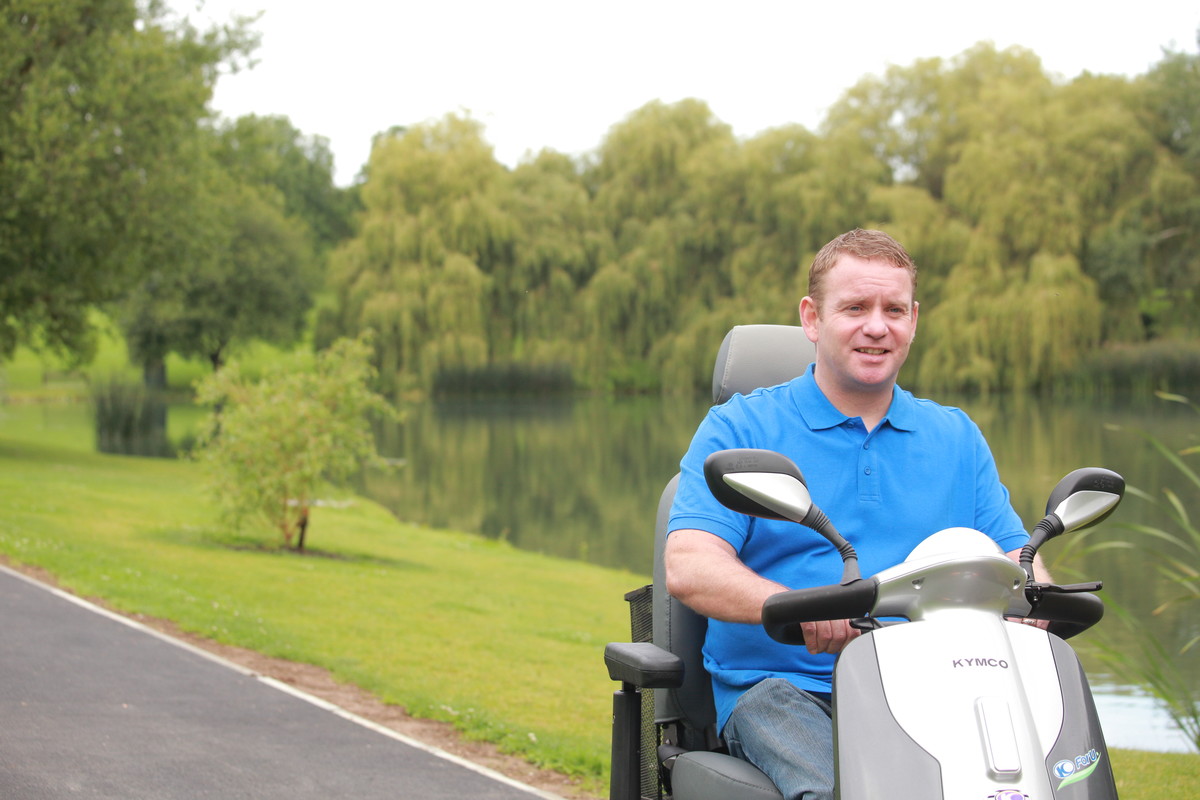 Man in scooter driving along path in park