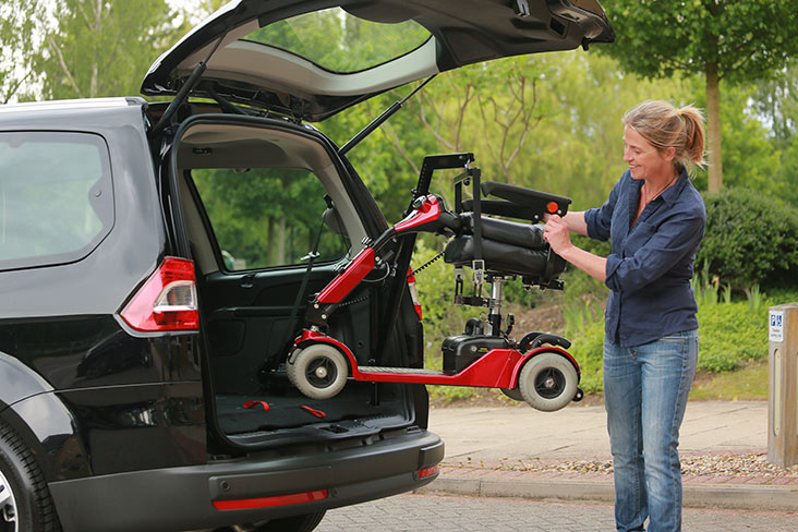 Lady putting electric scooter into boot of car