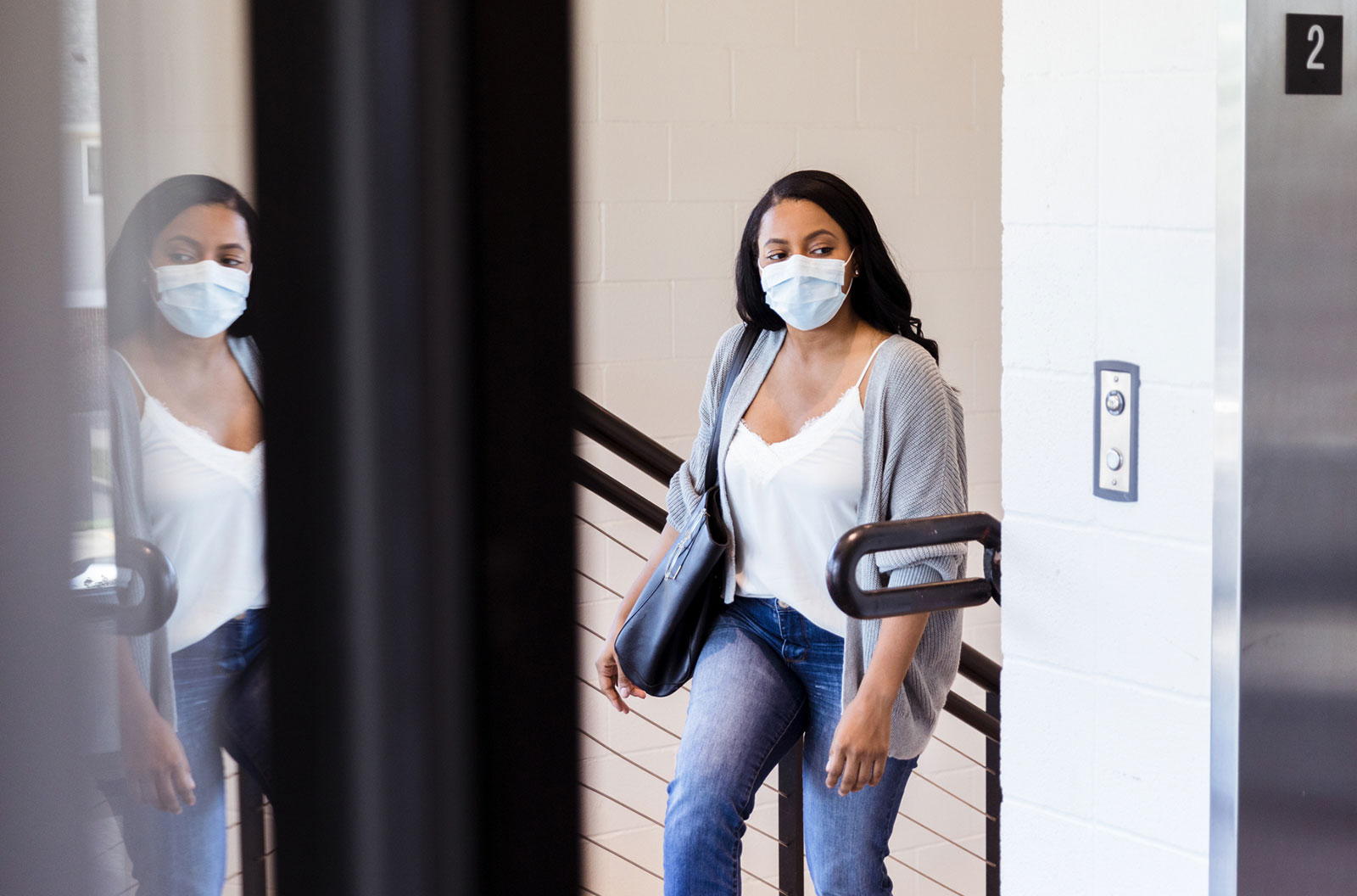A woman wearing mask goes upstairs to a doctor's office