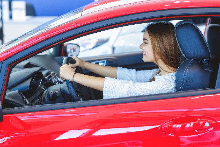 young first-time new driver sitting in red car