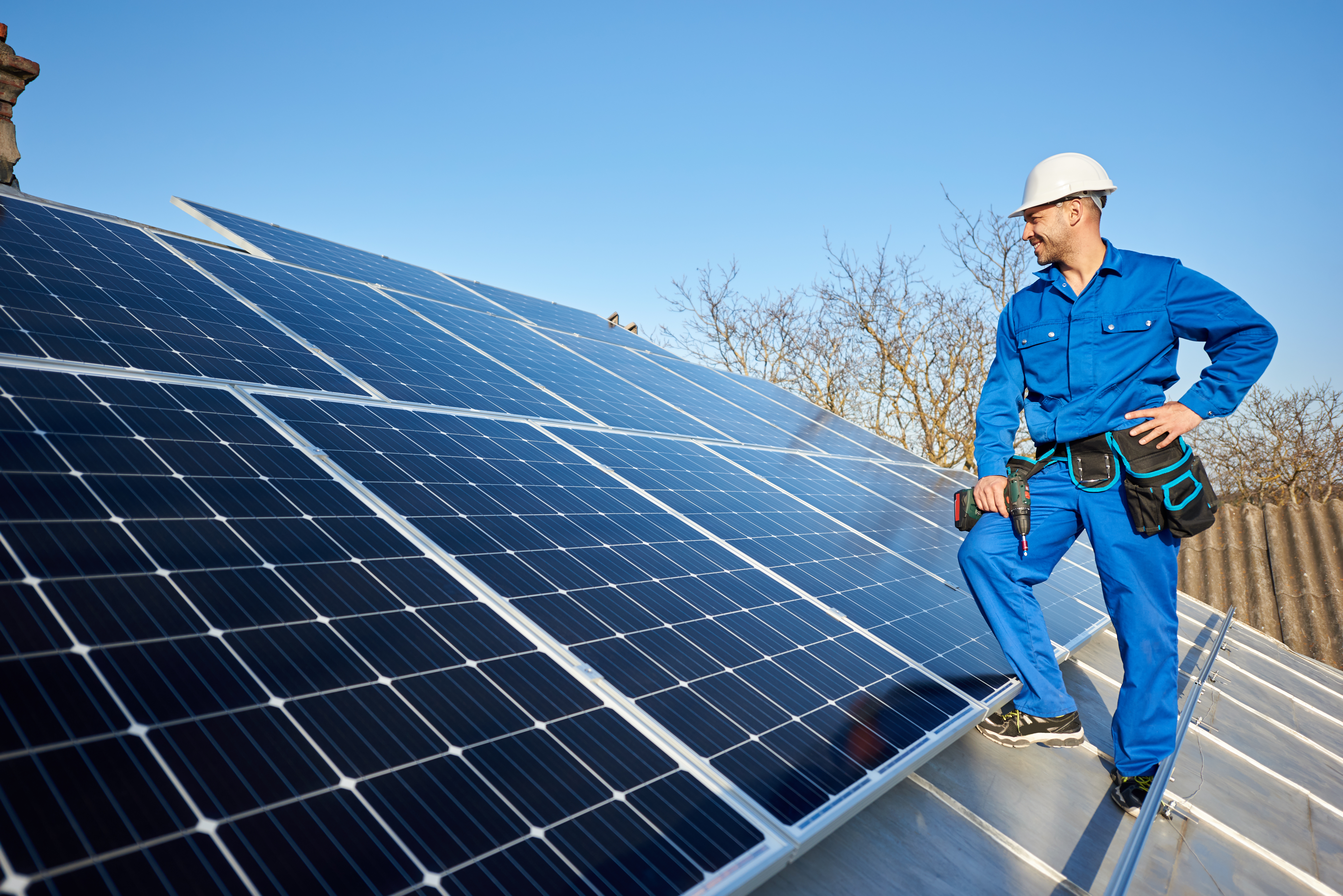 Electrician mounting solar panel on roof of modern house