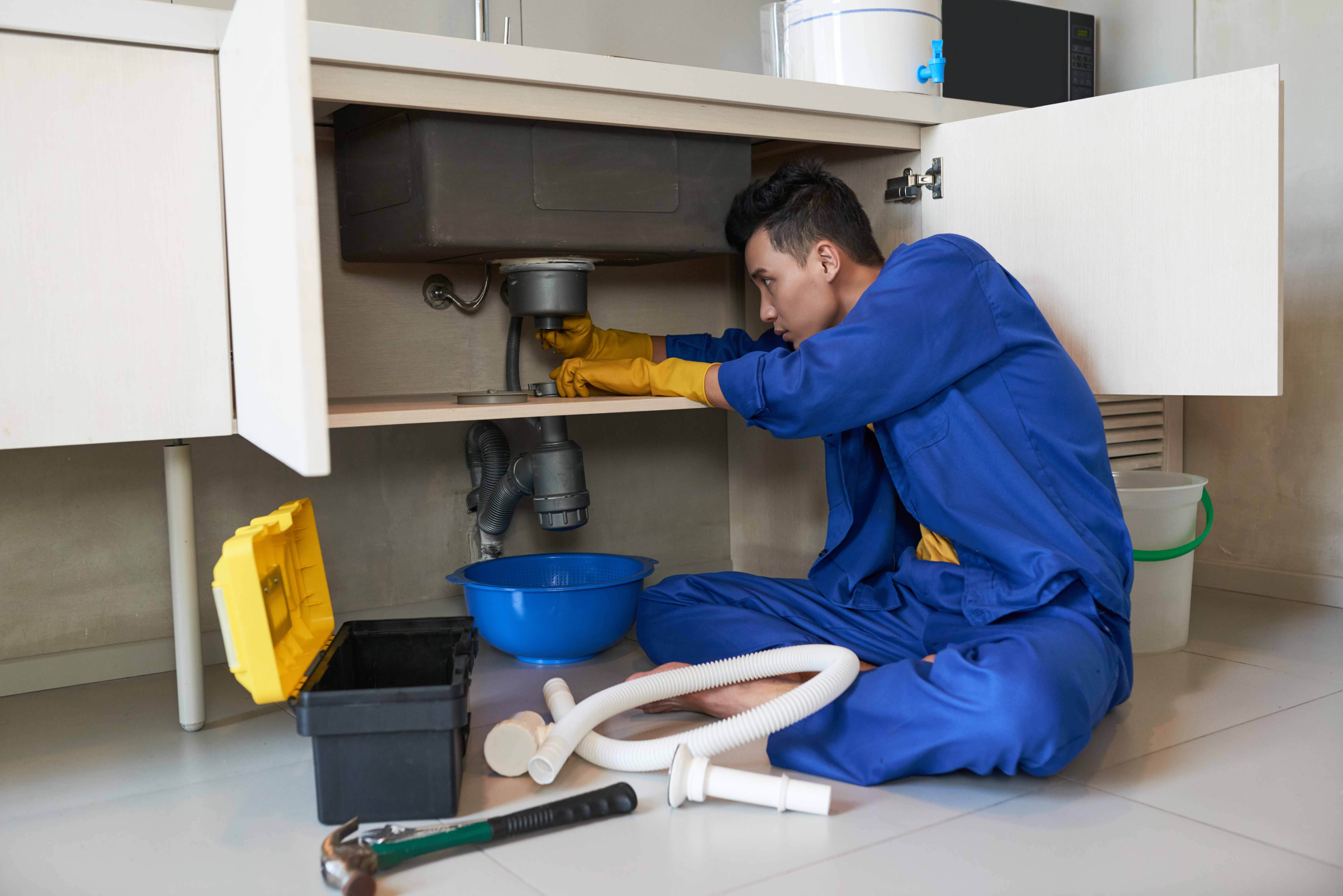 asian-plumber-blue-overalls-clearing-blockage-drain.jpg