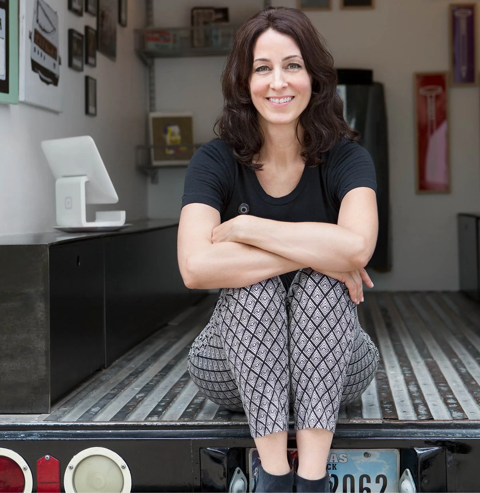 Photo of a woman sitting in the back of a mobile art gallery truck with a Square Stand in the background