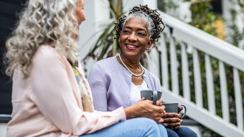 Senior women having coffee in front of suburban home