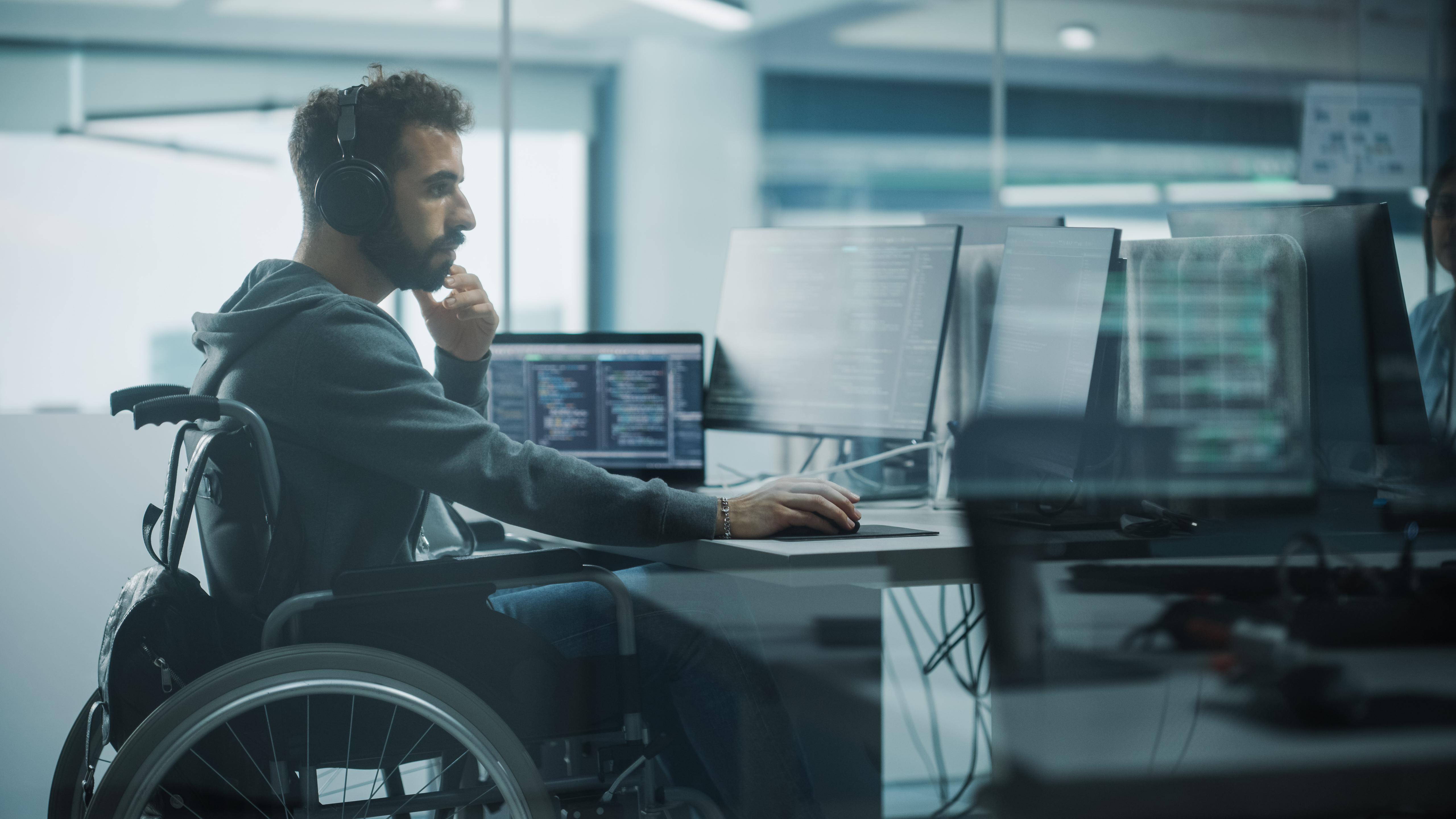 Disability-Friendly Office: Brilliant IT Programmer with Disability in a Wheelchair Working on Desktop Computer. Male Specialist Create Inspirational Software. Engineer Develop Innovative App, Program