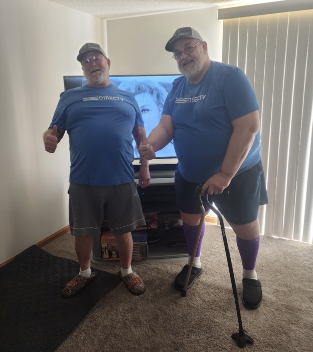 alt="Two men holding hands and standing in a roomDescription automatically generated with low confidence"