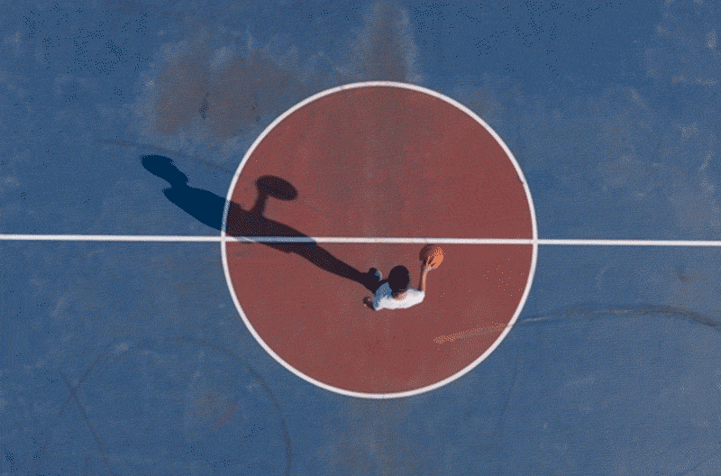 Aerial view of man inside of a basketball court dribbling a ball