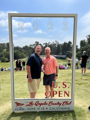 Two men standing in a signDescription automatically generated with low confidence