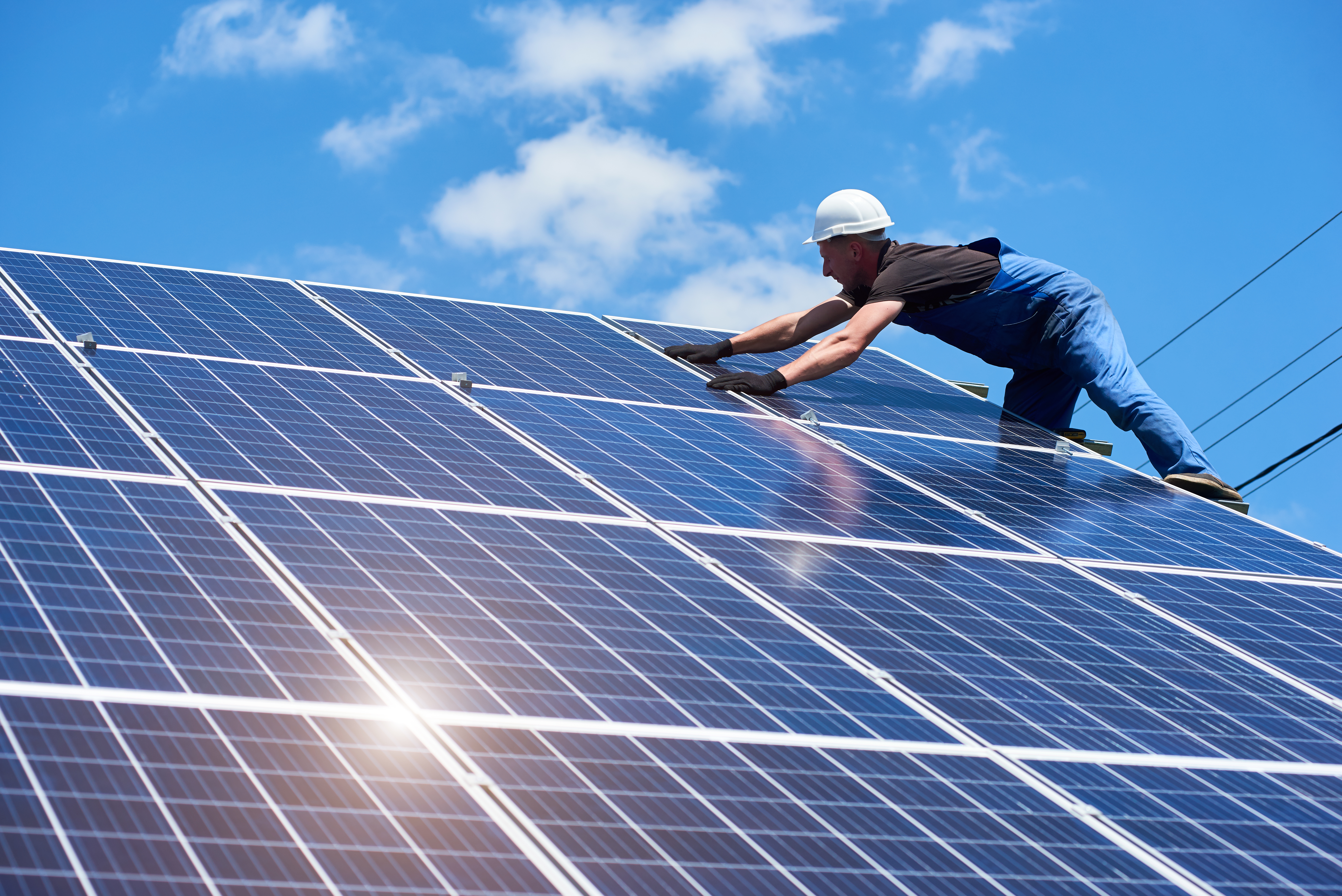 Professional worker installing solar panels on the green metal construction