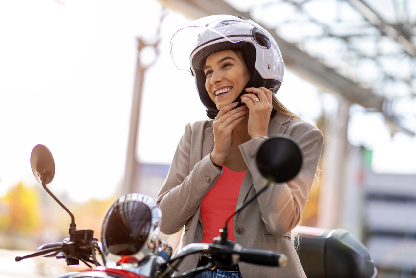 Ženska zapenja čelado za varn ovožnjo z mopedom - simbolna slika za zavarovanje motorja ali mopeda