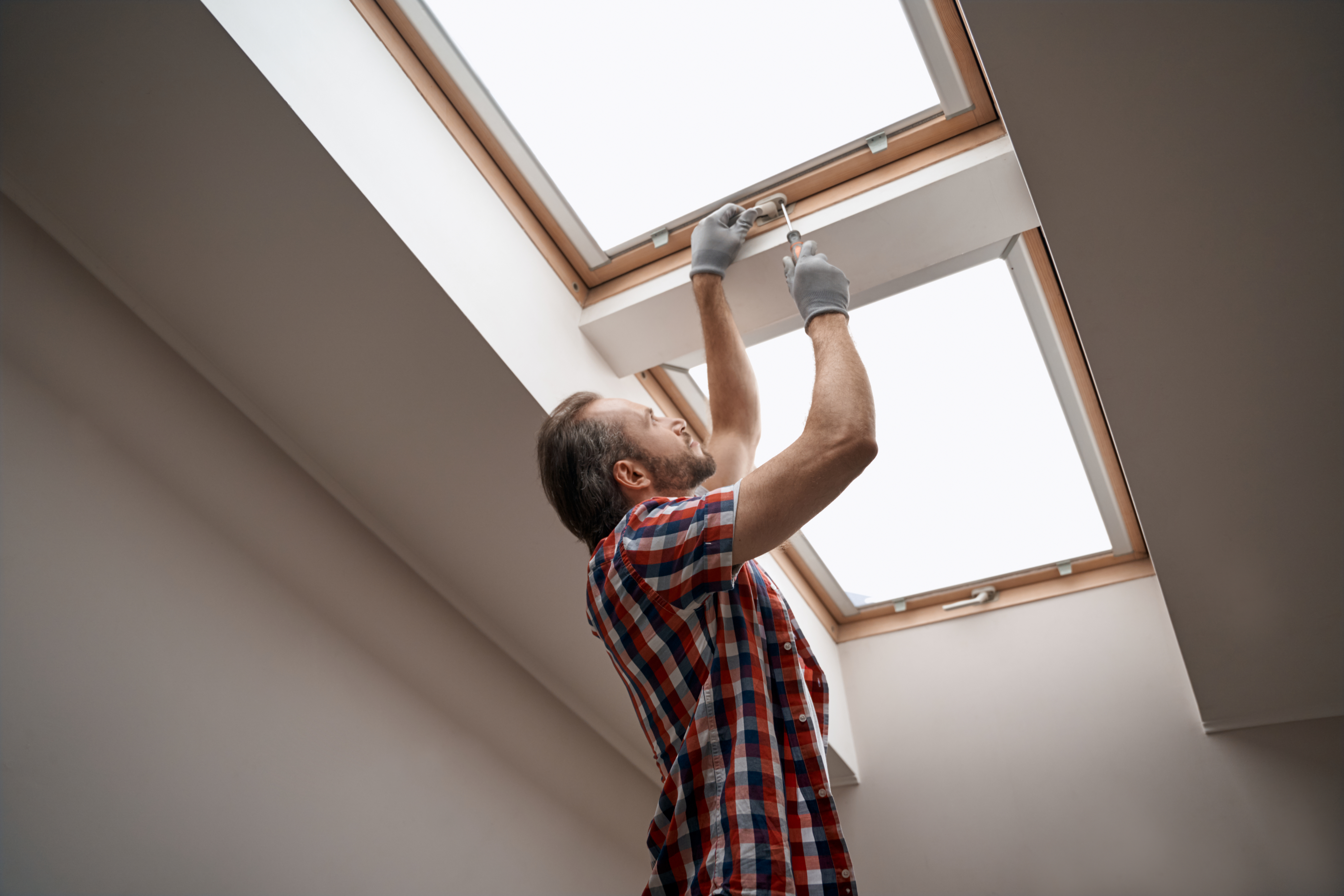 Young caucasian worker screwing skylight window handle