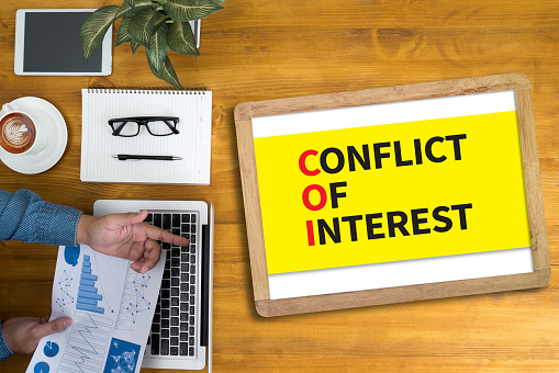 COI as CONFLICT OF INTEREST Businessman working at office desk and using computer and objects, coffee, top view,