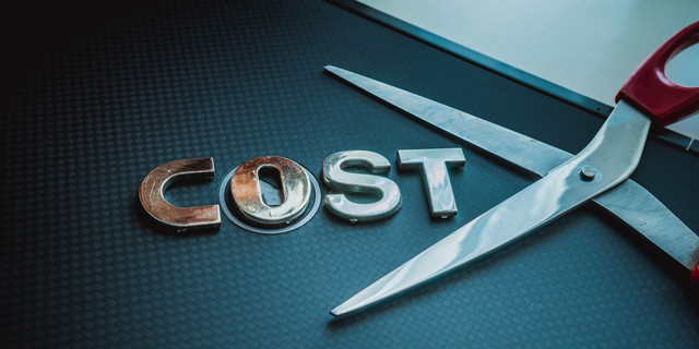 Stainless steel scissor next to word cost. Concept of cost-cutting