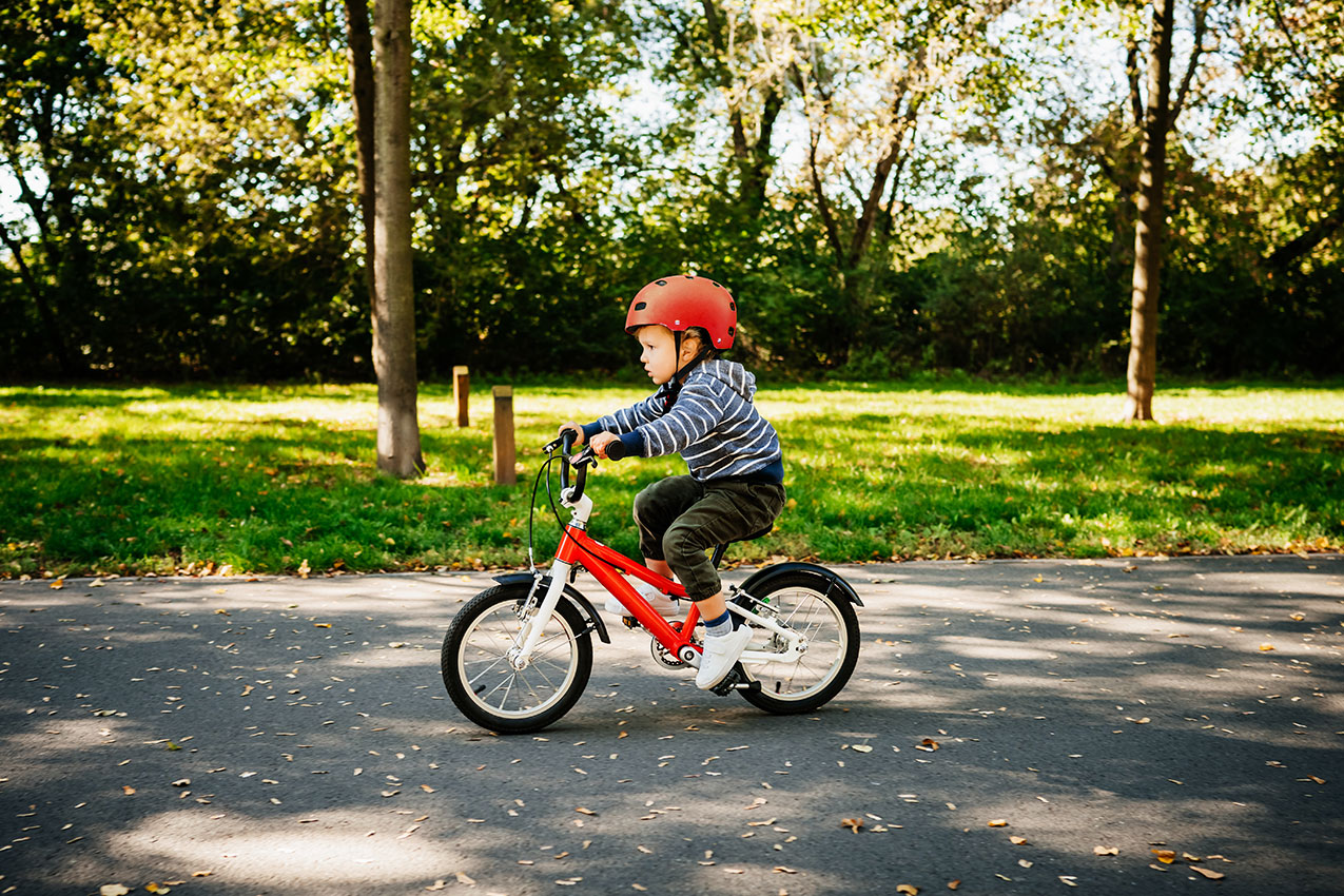 Deček na rdečem kolesu se uči voziti kolo